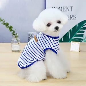 Small white dog wearing a breathable blue and white striped summer pet vest indoors