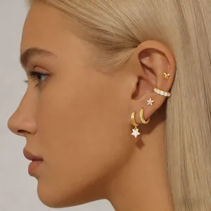 Close-up of gold butterfly and star earring set with stones on model's ear
