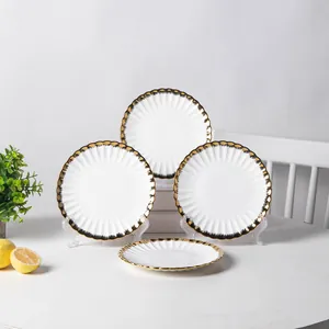 Set of premium white ceramic dinner plates with elegant gold wavy rims on a table