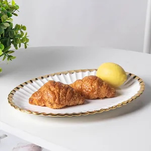 Detailed view of white ceramic plate with gold scalloped edge holding croissants