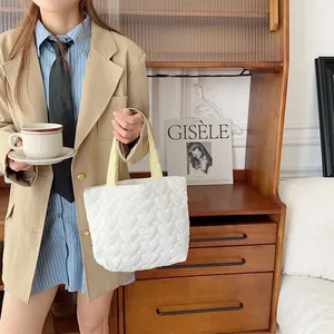 Lifestyle-Detail: Weiße gesteppte Tragetasche mit Herzmuster, von einem Model gehalten.