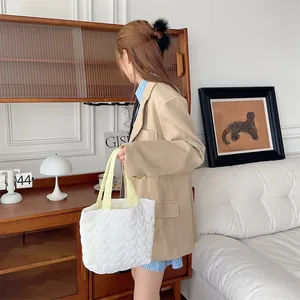 Detailansicht einer weiß gesteppten Herzmuster-Tragetasche mit gelben Griffen im Lifestyle-Stil.
