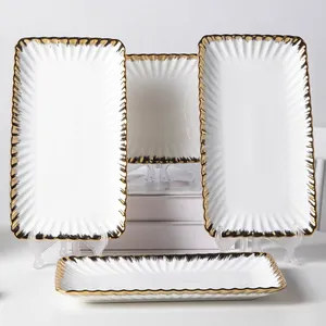 Detailed view of elegant white ceramic plates with scalloped gold rims on stands