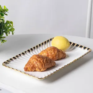 Detail shot showing the elegant gold trim on a white ceramic plate with food display.