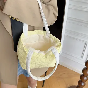 Detailansicht der weichen Textur einer gelben gesteppten Handtasche mit Herzmuster und Henkeln