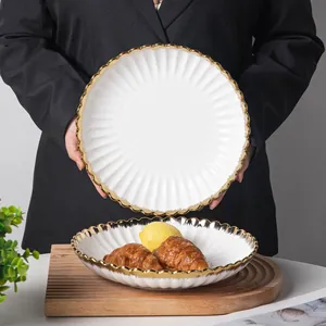 Elegant European white ceramic dinner plate with gold rim and fluted edges for dining