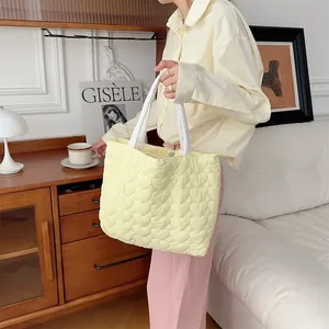 Detail einer niedlichen hellgelben gesteppten Tasche mit Herzmuster in Lifestyle-Umgebung.