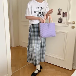 Detailansicht der lila gesteppten Handtasche mit Herzmuster, getragen von einem Model.