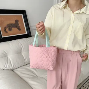 Detailansicht einer süßen rosa gesteppten Herz-Tragetasche von einem Modell.