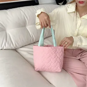 Nahaufnahme einer niedlichen rosa gesteppten Tasche mit Herzmuster, von Model gehalten