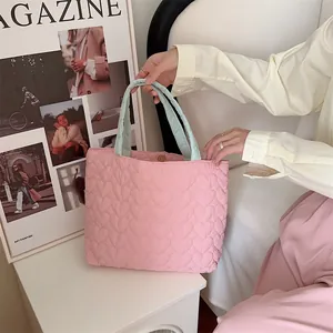 Nahaufnahme einer rosa gesteppten Tragetasche mit Herzmuster und hellgrünen Griffen