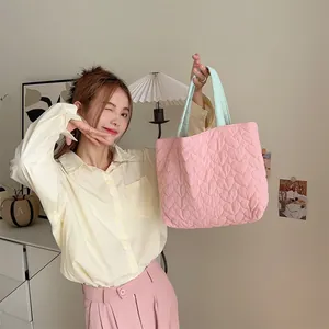 Lifestyle-Detail mit einem Modell, das eine rosa herzgesteppte Stofftasche hält