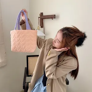 Detailansicht der niedlichen gesteppten Handtasche mit Herzmuster, von Modell gehalten.