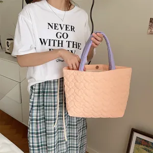 Nahaufnahme des weichen gesteppten Herzmusters auf dieser lila-aprikosen Handtasche