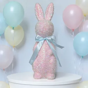 Detailed view of a pink glittery Easter bunny figurine with a blue ribbon bow