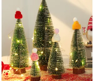 Detailansicht von mini beflockten Weihnachtsbäumen mit bunten Strickmützen und Lichter