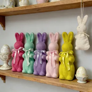 Figurines de lapins de Pâques floqués colorés avec rubans sur une étagère en bois