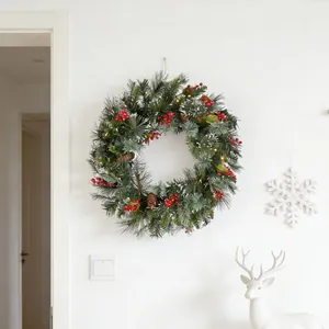 Detailansicht eines Weihnachtskranzes mit roten Beeren und warmen Lichtern