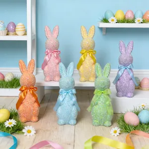 Nahaufnahme von glitzernden bunten Osterhasenfiguren mit passenden Seidenschleifen