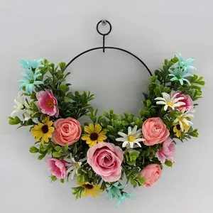 Decorative floral wreath with pink roses and daisies on a circular black metal hoop frame