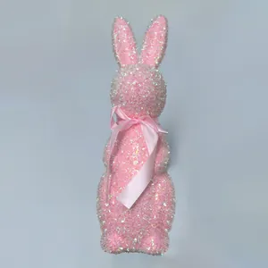 Close-up detail of a glittering pink Easter bunny figurine with a decorative silk bow