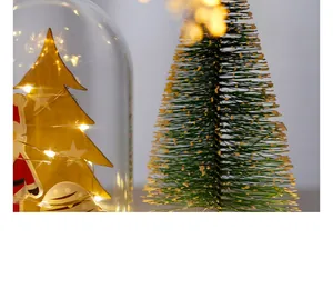 Nahaufnahme einer beleuchteten Weihnachtsglaskuppel und Mini-Kieferndekoration
