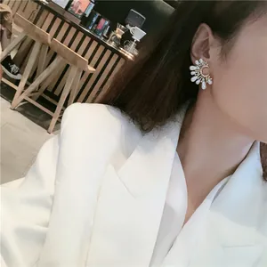 Close-up detail of elegant semi-circle pearl drop earrings worn by a model in a café