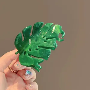 Detailed macro view showing marbled green acetate texture on a monstera leaf hair claw clip