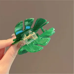 Detailed view of a green monstera leaf-shaped acetate hair claw clip with marble texture