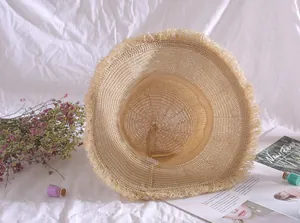 Detail view of the inner lining and frayed brim of a wide-brimmed summer straw hat.
