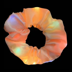 Detailed view of an orange glowing LED hair scrunchie with vibrant light effects