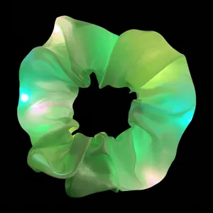 Detail view of a green LED glowing hair scrunchie with multi-color lights on black background