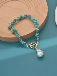 Close-up of turquoise chip bracelet with gold toggle clasp and baroque pearl pendant