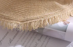 Detailed macro view of the breathable woven straw texture and frayed fringe edge of a sun hat