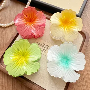 Detailed view of four colorful gradient flower-shaped hair claw clips on a wooden tray