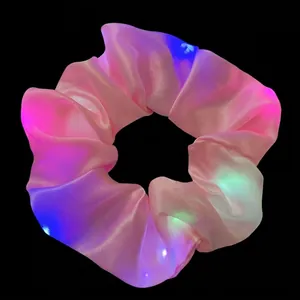 Close-up view of pink satin LED scrunchie with vibrant multi-color glowing lights
