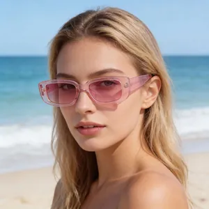 Stylish retro small frame pink sunglasses for women worn by a model at a sunny beach