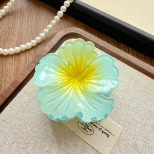Macro detail of a stylish translucent gradient green flower hair claw clip with yellow center