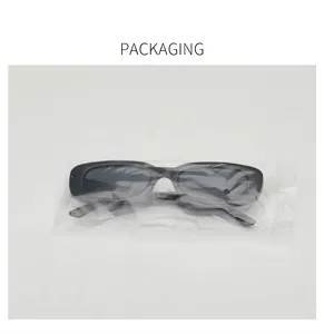 Detailed view of black retro small frame sunglasses in transparent plastic packaging bag