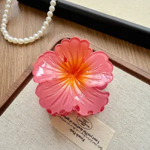 Detail view of a pink and orange gradient flower hair claw clip with delicate petals
