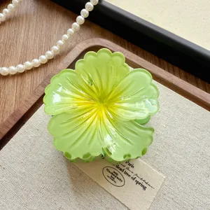 Detailed macro view of a lime green gradient flower hair claw clip resting on fabric