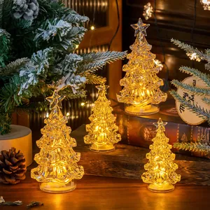 Set of glowing mini LED crystal Christmas trees with warm lights on a wooden desk