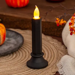 Dettaglio di candela LED nera senza fiamma con luce gialla calda su un tappeto accogliente