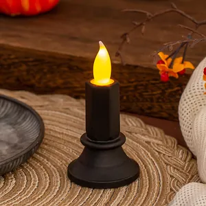 Candela LED nera senza fiamma con fiamma gialla tremolante su una tovaglietta tessuta