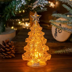 Atmospheric glowing LED mini Christmas tree on a wooden table with festive background decor