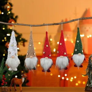 Detailed view of five colorful Christmas gnome ornaments hanging on a rustic branch.