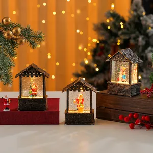 Detailed view of three Christmas house snow globes with warm lights and swirling glitter
