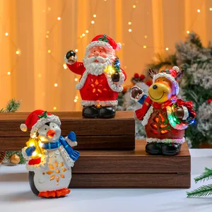 Drei musikalische Weihnachtsfiguren aus Harz leuchten auf einem Holzregal in warmer Atmosphäre