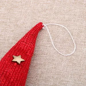 Close-up detail of red knitted Christmas ornament hat with gold star and hanging loop