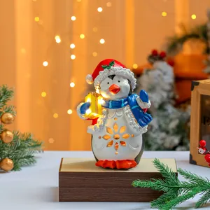 Nahaufnahme einer leuchtenden Pinguinfigur aus Harz mit LED-Schneeflocken